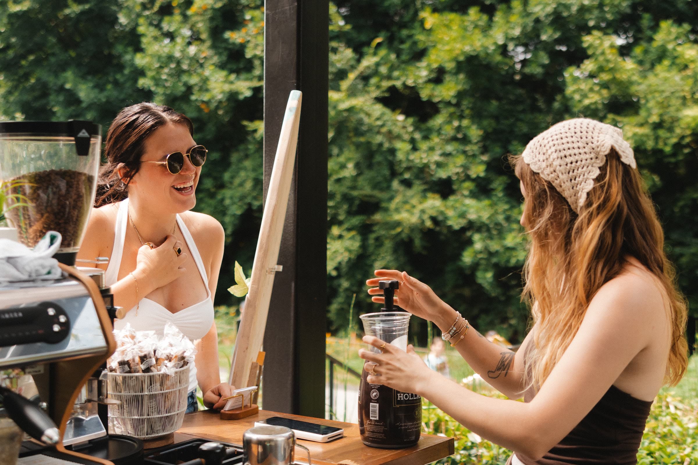 A coffee cart owner serving a customer outdoors
